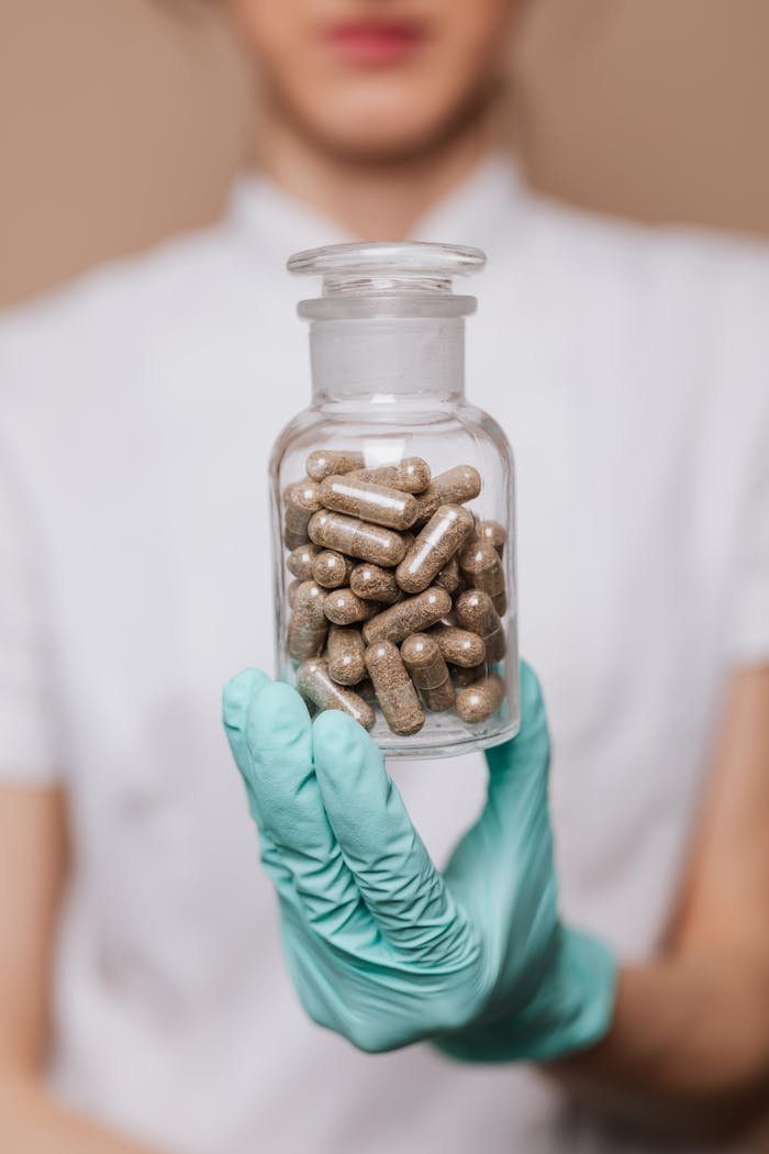 A healthcare worker holding a glass bottle filled with brown capsules, highlighting clinical care.